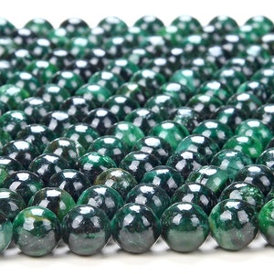 May include: A close-up of a strand of dark green gemstone beads. The beads are round and smooth, with a slightly mottled surface.