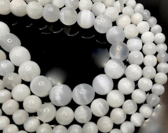 May include: A strand of white gemstone beads, with a smooth, polished finish. The beads are round and have a subtle shimmer.