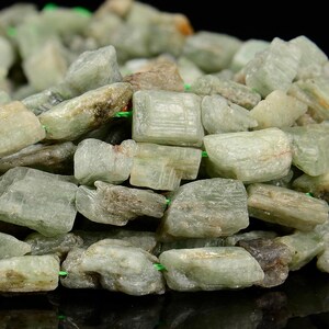 May include: A strand of green and gray gemstone beads. The beads are rough and have a natural, unpolished look. They are strung on a green elastic cord.