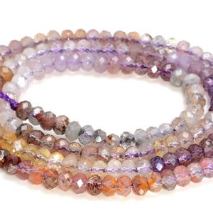 Puede incluir: Hebras de cuentas de piedras preciosas facetadas en tonos morado, naranja, marrón y transparente. Las cuentas están ensartadas en un cordón morado. Las piedras preciosas tienen un aspecto pulido. Las cuentas se utilizan probablemente para la fabricación de joyas.