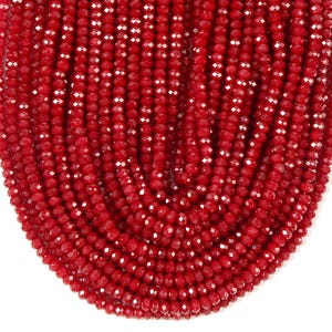 May include: A collection of numerous small, vibrant red crystal beads arranged in parallel vertical strands. Each bead features a multi-faceted surface that reflects light, creating a sparkling effect across the uniform, deep red color of the beads.