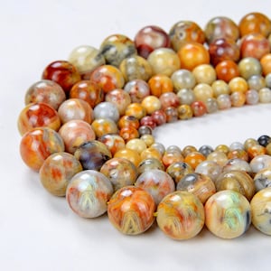May include: A strand of round, multi-colored agate beads. The beads are a mix of brown, orange, yellow, and white with swirling patterns.