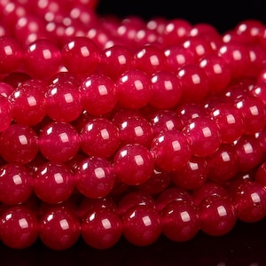 May include: A strand of deep red gemstone beads. The beads are round and smooth, with a glossy finish.