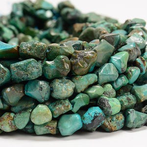 May include: A strand of turquoise gemstone beads, featuring a mix of irregular shapes and sizes. The beads are a vibrant green-blue color with brown and black markings.