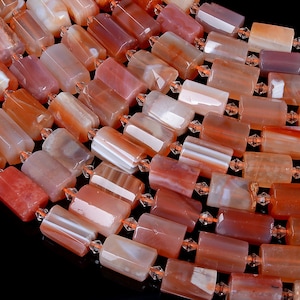 Puede incluir: Una hebra de cuentas de cornalina, con una mezcla de colores naranja y blanco. Las cuentas son rectangulares y tienen un acabado pulido.