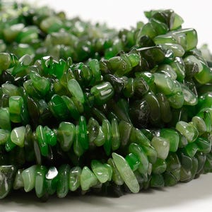 May include: A strand of green jade chip beads. The beads are irregular in shape and have a smooth, polished finish.