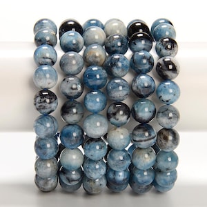 May include: A bracelet made of round aquamarine beads, each displaying a mix of light and dark blue hues with black inclusions. The beads are strung together, creating a marbled effect. The bracelet is a beautiful piece of jewellery.