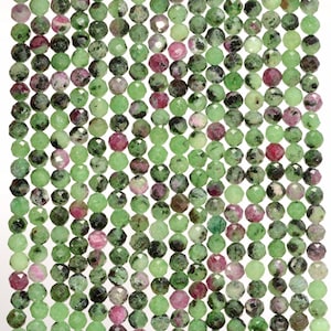 May include: A strand of faceted green and pink gemstone beads. The beads are round and have a smooth, polished finish.