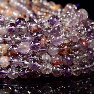 May include: A strand of round, translucent purple and clear beads with hints of brown and silver. The beads are approximately 8mm in diameter.