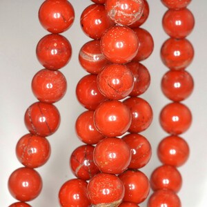 May include: A strand of red jasper beads, each bead is round and polished, with a smooth, glossy finish.
