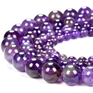 May include: A strand of round, purple amethyst beads. The beads are smooth and polished, with a slight variation in color and size.