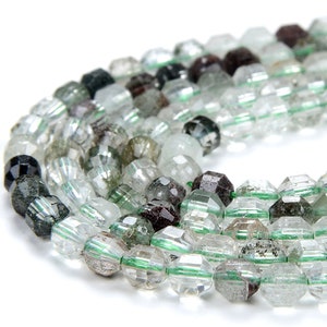 Puede incluir: Una hebra de cuentas de cuarzo transparente facetadas con inclusiones verdes y negras. Las cuentas tienen un diámetro aproximado de 8 mm y una forma facetada ligeramente irregular.