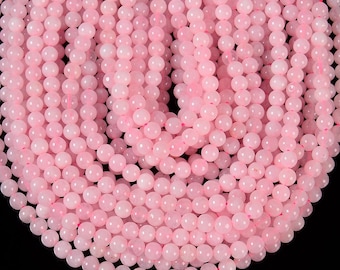 Puede incluir: Primer plano de hilos de cuentas redondas de piedras preciosas de color rosa claro. Las cuentas están ensartadas, creando una superficie densa y texturizada. Las cuentas son uniformes en tamaño y color, con una apariencia suave y translúcida. El fondo es negro.