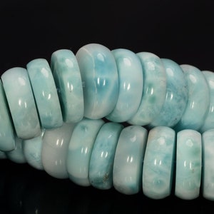 May include: A strand of light blue gemstone beads. The beads are round and have a smooth, polished finish. The beads are arranged in a row, with the ends of the strand overlapping.