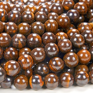 May include: A close-up of a strand of brown and black gemstone beads. The beads are round and have a smooth, polished finish. The beads are arranged in a random pattern.