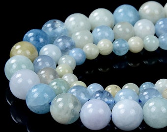 May include: A strand of light blue, pale blue, and green aquamarine beads. The beads are round and smooth, and they are strung together on a clear thread.