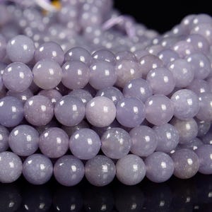 May include: A strand of lavender-coloured gemstone beads. The beads are round and smooth, with a slightly iridescent finish.