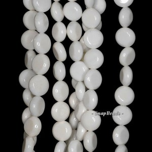 May include: A strand of white round glass beads. The beads are smooth and have a glossy finish.  -SnapBeads-