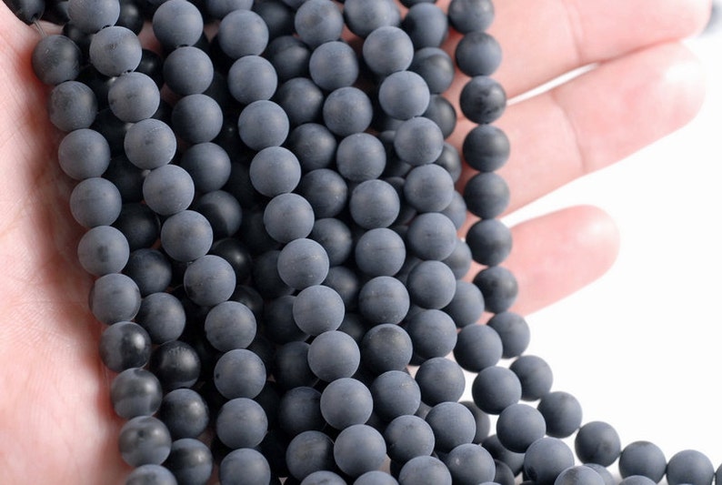 May include: A strand of dark gray matte round beads. The beads are smooth and have a slightly textured surface.