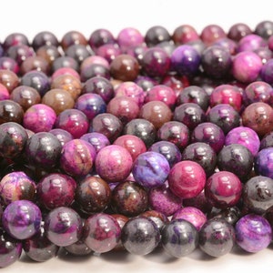 May include: A strand of round, purple and brown agate beads. The beads have a mottled, marbled appearance.