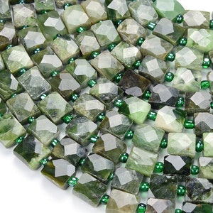 Könnte beinhalten: Eine Strähne grüner Edelsteinperlen mit facettierter quadratischer Form. Die Perlen sind auf einem Draht mit kleinen grünen Abstandshaltern aufgefädelt.