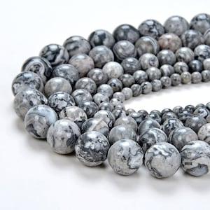 May include: A strand of gray and black marbled round beads. The beads are smooth and polished, with a natural, organic look.