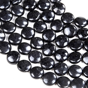 Puede incluir: Una hebra de cuentas de obsidiana negra, cada cuenta es lisa y redonda con una forma ligeramente aplanada.