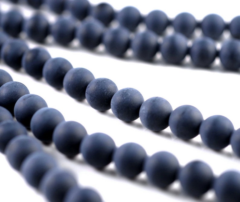 May include: A strand of dark blue round beads, made of a matte material, strung together to form a necklace or bracelet.