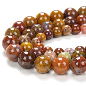 May include: A strand of round, polished agate beads in shades of brown, red, and yellow. The beads have a mottled, marbled appearance.
