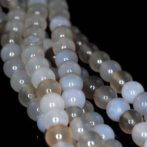 May include: A strand of light gray agate beads. The beads are round and smooth, with a slight sheen.