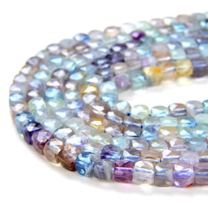 May include: A strand of faceted gemstone beads in shades of blue, purple, and yellow. The beads are square-shaped and have a glossy finish.