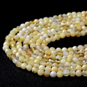 May include: A strand of faceted, round, yellow opal beads. The beads are translucent and have a milky white color with hints of yellow and brown.