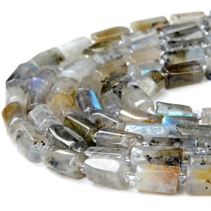 May include: A strand of iridescent grey and white labradorite gemstone beads. The beads are faceted and have a rectangular shape.