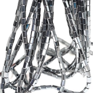 May include: A strand of silver-toned hematite beads, each bead is a square tube shape. The beads are stacked and overlapping, creating a textured look.