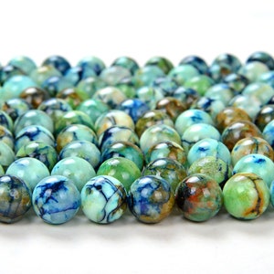 Peut inclure: Gros plan sur une collection de perles sphériques polies, dans des tons de bleu, vert et marron. Les perles présentent un aspect marbré avec des motifs complexes et des variations de couleurs. Les perles sont disposées de manière rapprochée.