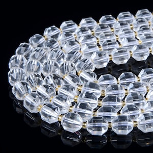 May include: A strand of clear crystal beads with gold accents. The beads are faceted and have a geometric shape.
