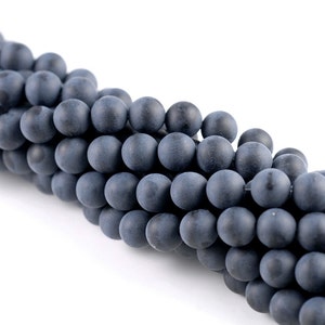 May include: A strand of dark gray matte round beads. The beads are smooth and have a slightly textured surface.