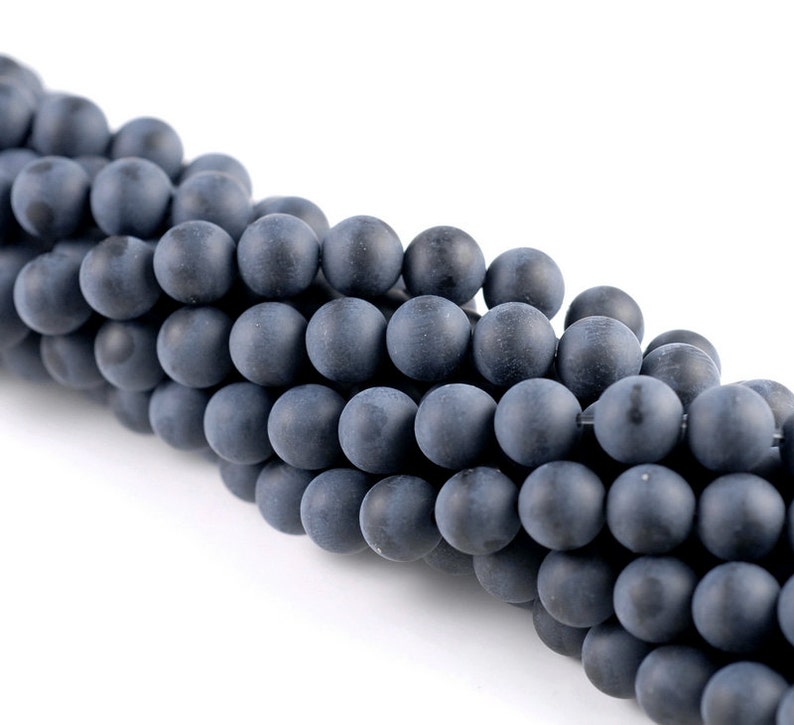 May include: A strand of dark gray matte round beads. The beads are smooth and have a slightly textured surface.