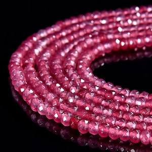 Puede incluir: Una hebra de cuentas de piedras preciosas facetadas de color rosa. Las cuentas son redondas y tienen un acabado liso y pulido. Las cuentas están enhebradas en un hilo transparente y están listas para ser utilizadas en la elaboración de joyas.