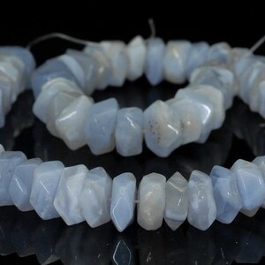 May include: A strand of light blue gemstone beads, each bead is faceted and has a unique shape. The beads are strung on a thin thread and are ready to be used for jewelry making.
