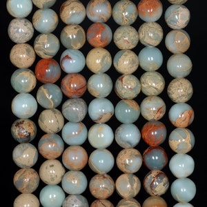 May include: A strand of round, smooth, light blue, brown, and red jasper beads. The beads have a mottled, marbled appearance.
