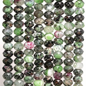 May include: A strand of faceted green, black, and pink gemstone beads. The beads are oval shaped and have a variety of patterns and colors.