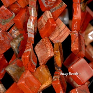 May include: A strand of red, orange, and brown jasper beads. The beads are square shaped and have a polished finish. The beads are strung on a clear elastic cord.