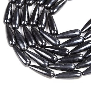 May include: A strand of black gemstone beads, each bead is shaped like a teardrop. The beads are smooth and polished, with a glossy finish.