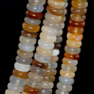 Peut inclure: Un brin de perles d'agate dans des tons de blanc, brun et orange. Les perles sont rondes et ont une finition lisse et polie.