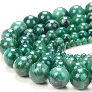 May include: A strand of green jade beads, each bead is round and polished, with a smooth, glossy finish. The beads are arranged in a circular pattern, with the largest beads in the center and the smaller beads on the outside.