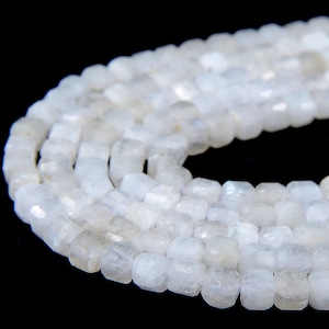 May include: A strand of white moonstone beads, each bead is faceted and has a square shape.