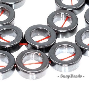 May include: A strand of black hematite beads with a hole in the center of each bead. The beads are strung on a red thread.