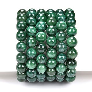 May include: A stack of round, green jade beads. The beads are smooth and polished, with a natural, marbled pattern.