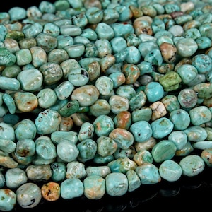 Może przedstawiać: Szereg koralików z turkusu, każdy koralik ma unikalny, nieregularny kształt z gładkim, polerowanym wykończeniem. Koraliki są jasnoniebiesko-zielone z brązowymi i białymi żyłkami.